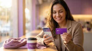 Mulher brasileira segura cartão roxo do Nubank e celular com app borrado mostrando solicitação online